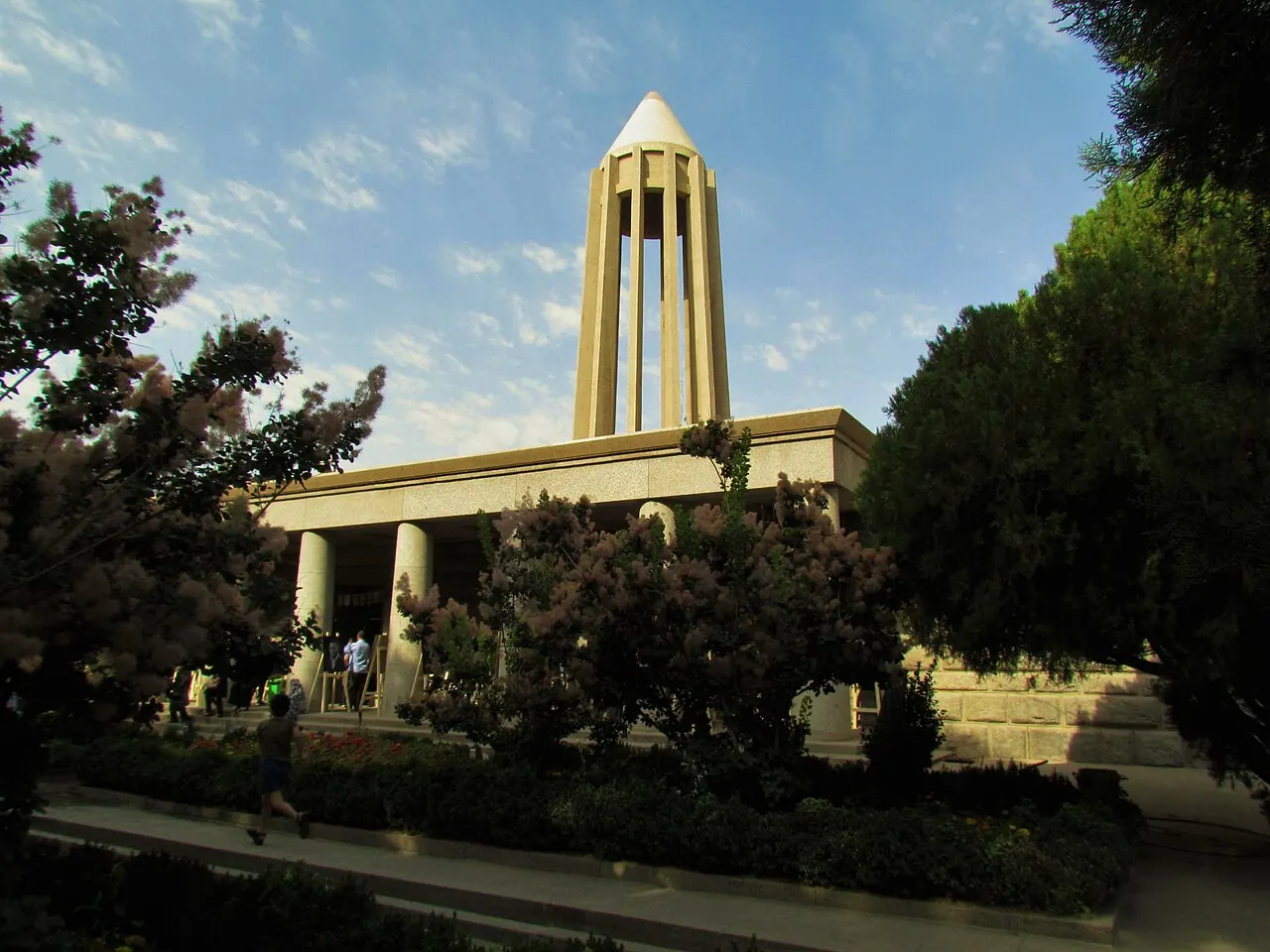 برج دوازده‌ستونی آرامگاه ابن سینا در همدان میان درختان باغ